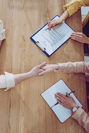 Handshake over table with clipboards